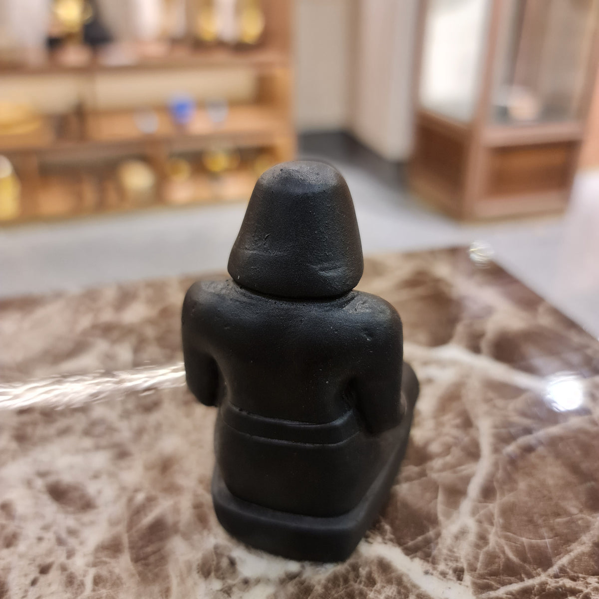 Black Ancient Egyptian seated scribe statue museum reproduction, three-quarter view