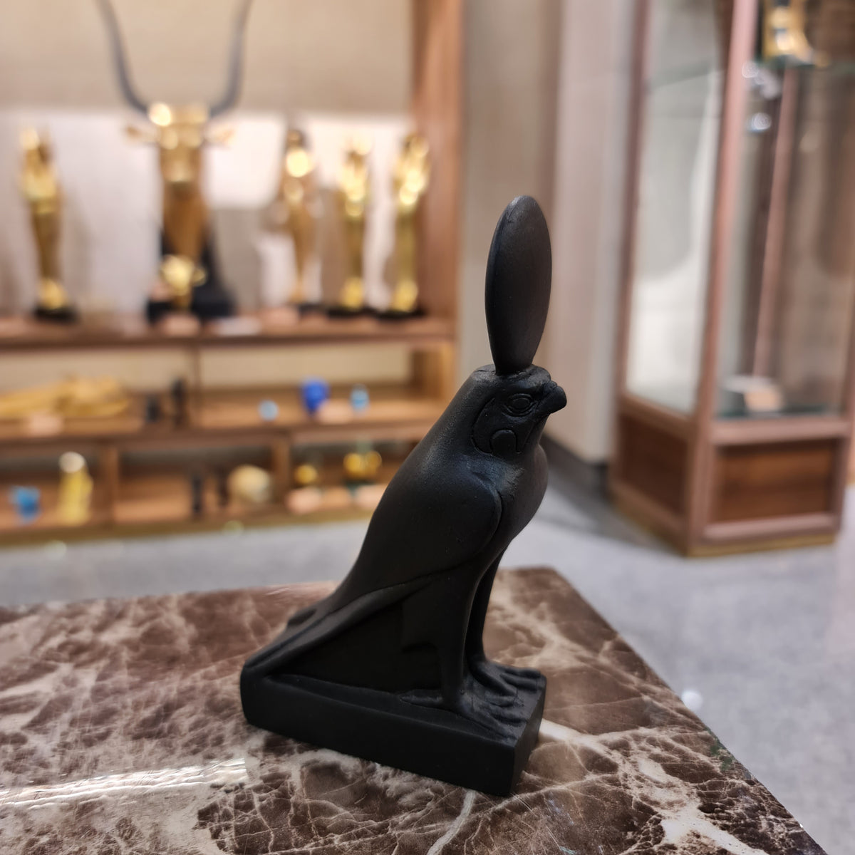 Black Horus falcon statue, side profile showing the sun crown