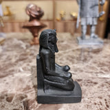 Black kneeling statue of King Thutmose III offering two nu vases, side angle
