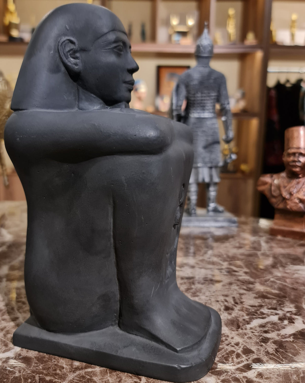 Side profile of the block statue showing the seated figure with crossed arms