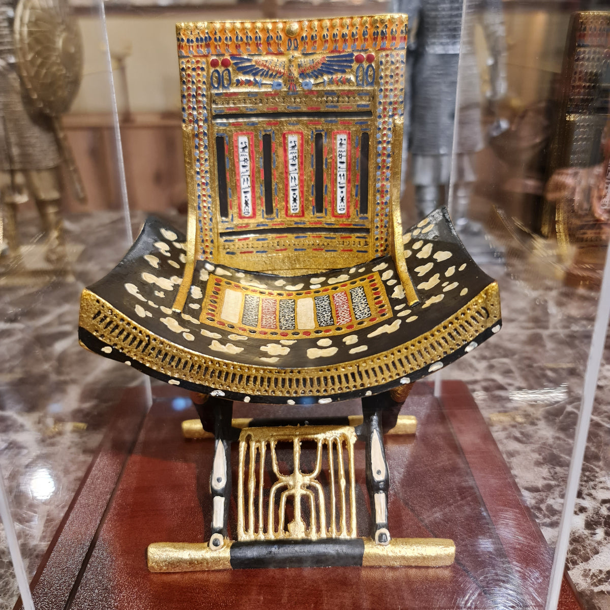 Full view of the ceremonial throne of King Tutankhamun in its plexiglass case, museum reproduction