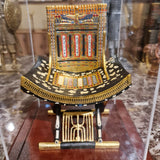 Full view of the ceremonial throne of King Tutankhamun in its plexiglass case, museum reproduction