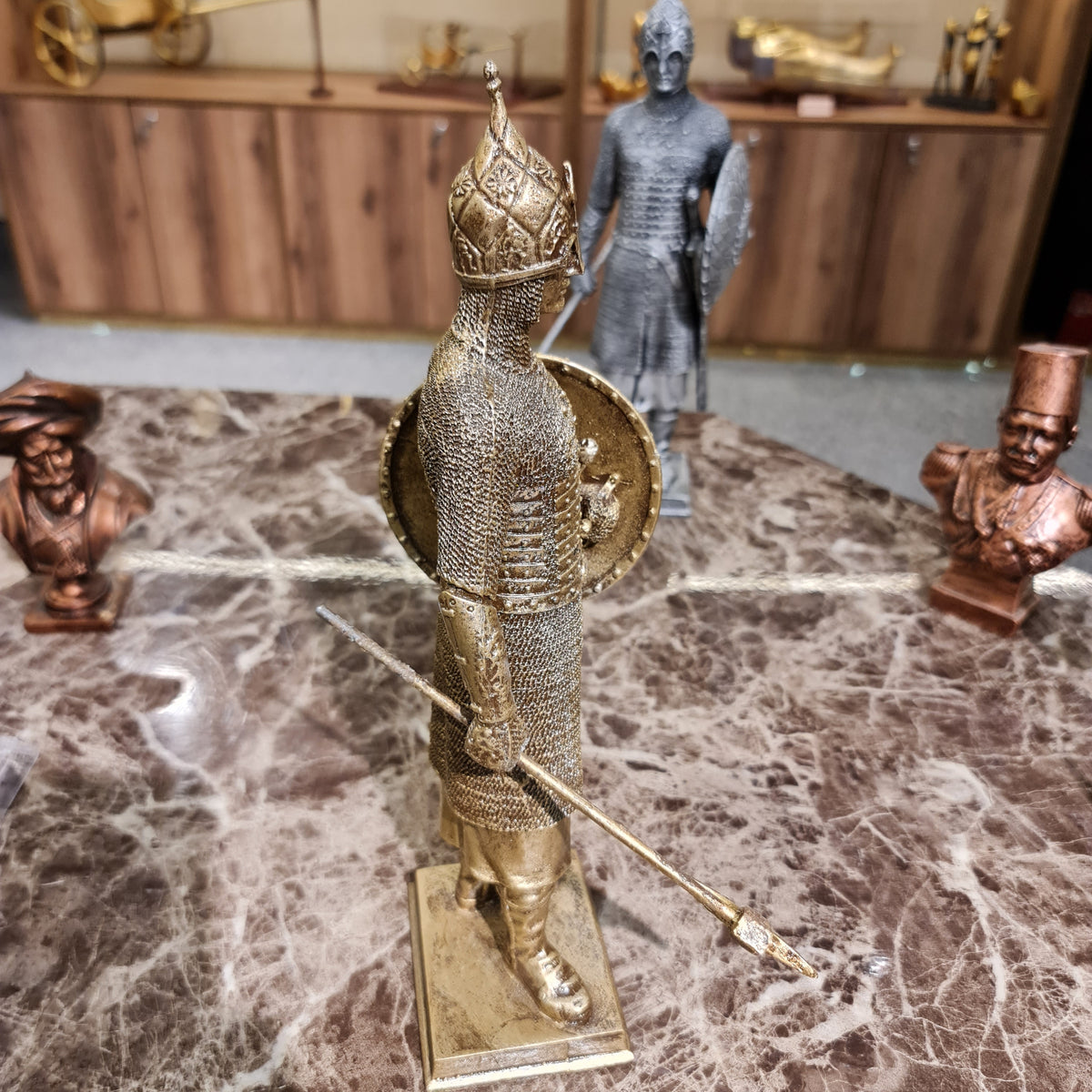 Side profile of the golden medieval knight sculpture showing armor detail