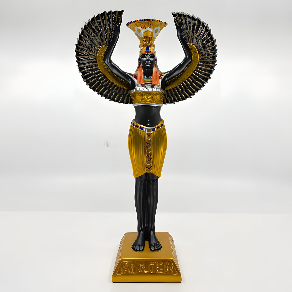 Black and gold Isis statue with a lit candle in the candle holder