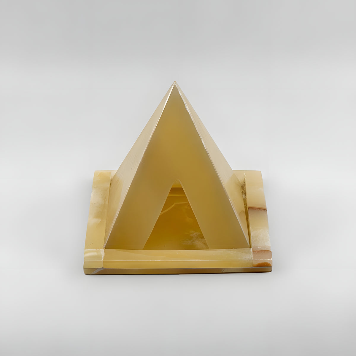 Alabaster pyramid candle holder museum reproduction, lit with a candle inside