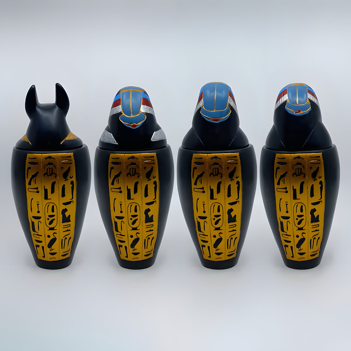 Polystone canopic jar set, museum reproduction — detail of Duamutef and Qebehsenuef jar lids
